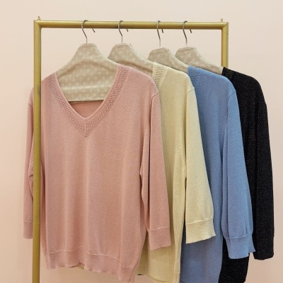 Camisolas de malha em diversas cores penduradas num cabide dourado