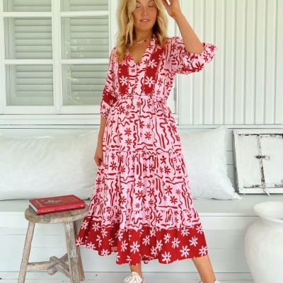 Vestido longo rosa com padrão floral vermelho em ambiente interior com mobiliário branco