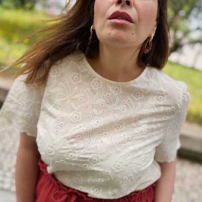 Mulher com blusa branca bordada e saia vermelha