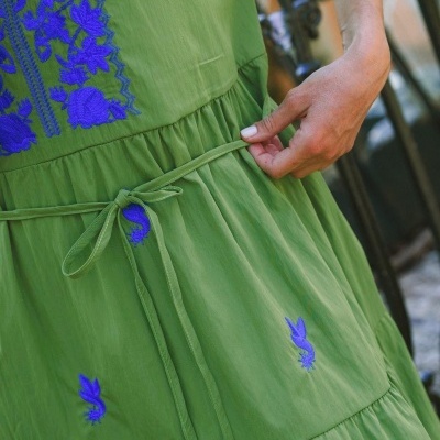 Vestido verde com bordados florais azuis e cintinho fino com mão segurando