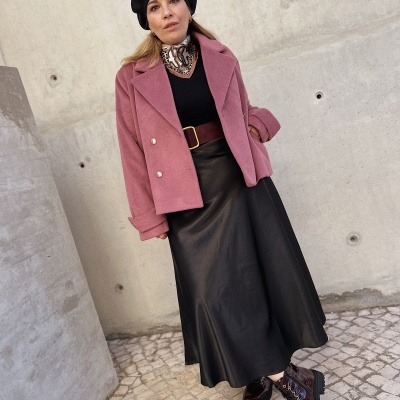 Mulher com roupa de outono em fundo urbano com parede de cimento e calçada portuguesa.