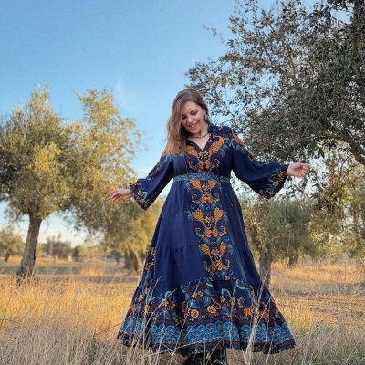 Mulher com vestido comprido azul escuro com padrão floral em campo