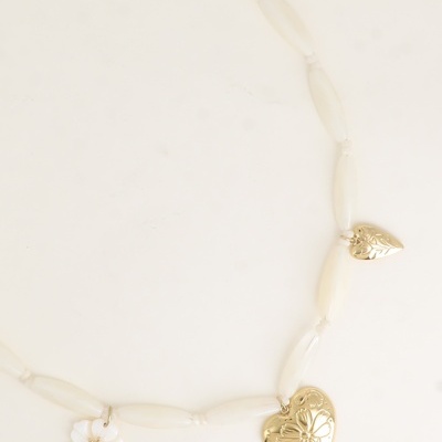 Colar branco com contas alongadas e pendentes dourados em forma de coração e flor