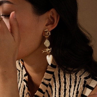 Brinco pendente dourado com pedras em tom marfim e detalhe de coração