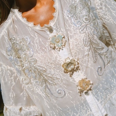 Blusa branca com bordados florais e botões decorativos flores