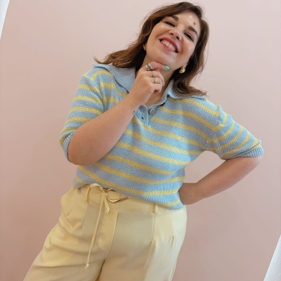 Mulher com camisola de riscas amarelas e azuis claras e calças amarelas largas