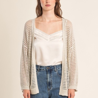 Mulher a usar cárdigan bege de malha aberta com blusa branca e calças de ganga azul