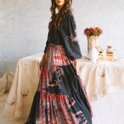 Vestido comprido feminino com padrão floral em vermelho e preto, mangas compridas e saia rodada em camadas.