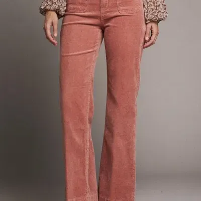 Calças rosa em veludo cotelê com bolsos frontais e botas castanhas.
