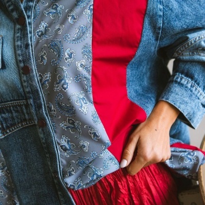 Casaco combinado com tecidos azuis, vermelho e ganga em ambiente interior