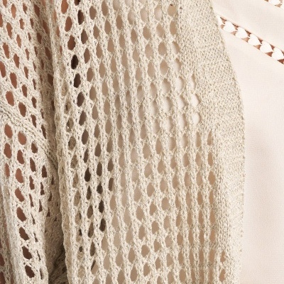 Malha bege luminosa sobre roupa creme com bordas de losangos vazados