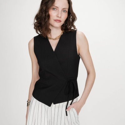 Blusa preta sem mangas com amarração lateral e calças brancas riscas pretas.