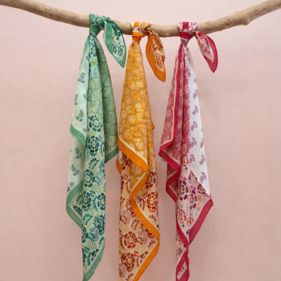 Três lenços florais coloridos pendurados numa rama de madeira