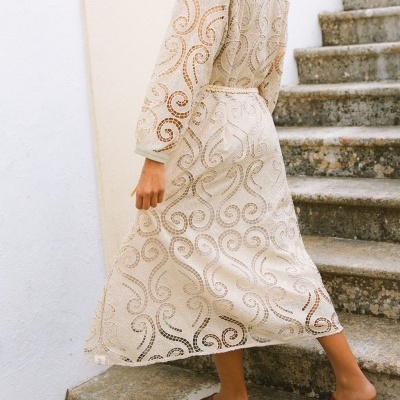 Vestido bege comprido de renda bordada usado por mulher a subir escadas de pedra