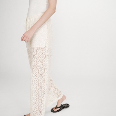 Calças femininas de renda creme com padrão floral e cordão, usadas com sandálias pretas.