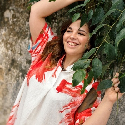 Camisa branca com estampados alaranjados e azuis em modelo feminino em ambiente exterior