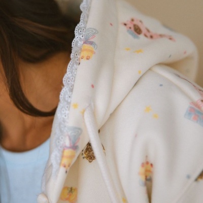 Casaco branco com capuz decorado com pequenas coroas e renda branca