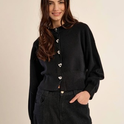 Mulher a vestir cardigan preto com botões em forma de coração e calças pretas de ganga