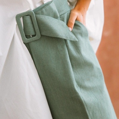 Calças verdes com cinto e camisa branca com botão decorativo