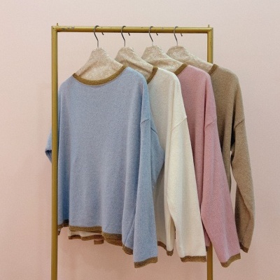 Quatro camisolas coloridas penduradas em cabideiro amarelo