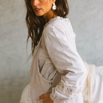 Blusa feminina bege com bordados florais nas mangas em ambiente interior