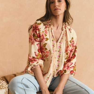 Blusa floral creme com calças de ganga azul clara em fundo salmão