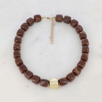 Colar com pedras marrons e elemento dourado sobre fundo branco.