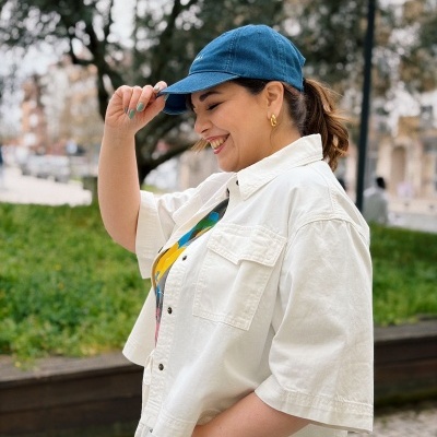 Mulher com boné azul e roupa branca ao ar livre
