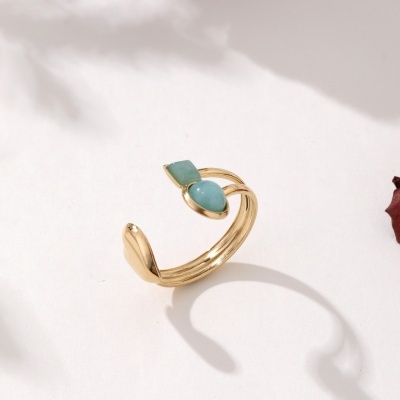 Anel dourado com pedras verdes sobre fundo branco