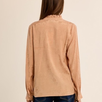 Blusa feminina bege claro com padrão floral e calças de ganga azuis vista de costas