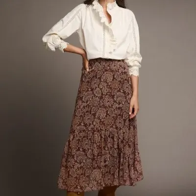 Mulher a usar blusa branca com rendas, saia longa castanha com padrão floral e botas castanhas