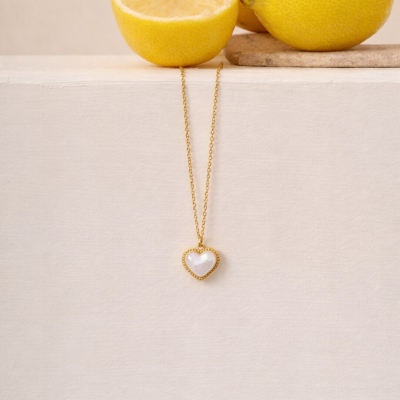 Colar com pendente de coração dourado e branco junto a limões