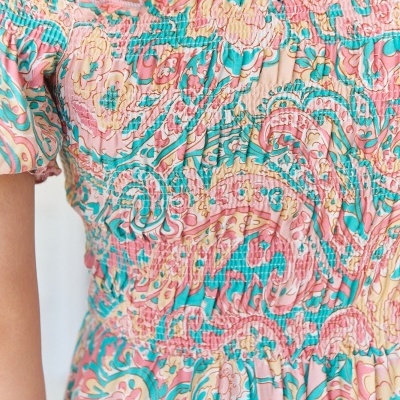 Vestido curto estampado com padrão floral e arabescos nas cores rosa e turquesa