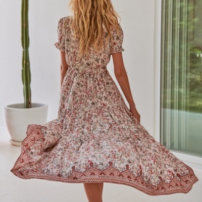 Vestido comprido feminino com padrão floral e mangas curtas bufantes visto pelas costas em cenário interior