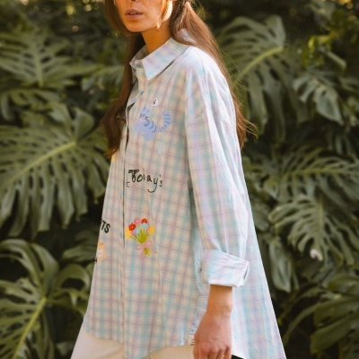 Blusa xadrez pastel com ilustrações e texto em ambiente natural