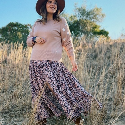 Mulher com chapéu castanho e roupa floral a caminhar em campo