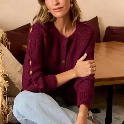 Mulher sentada com cardigan vinagre de malha grossa e calças de ganga claras