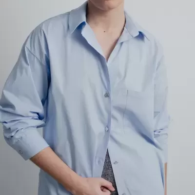 Camisa azul clara de tecido liso com botões e bolso ao peito