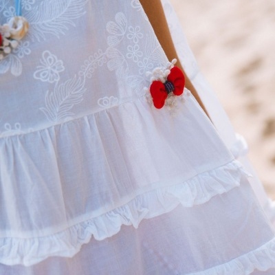 Vestido branco bordado com babados e laço vermelho