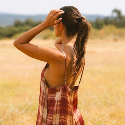Vestido aos quadrados em tons castanho e vermelho, visto de costas em campo aberto