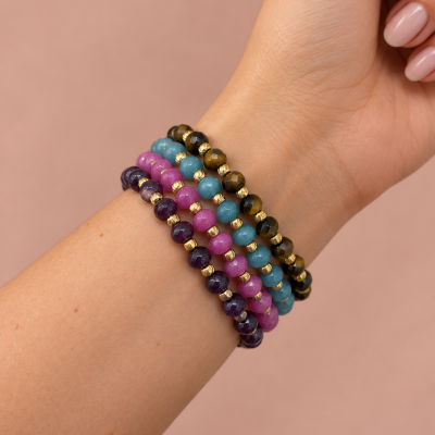 Pulseiras coloridas de contas facetadas em pulso feminino.