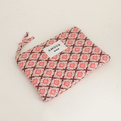 Bolsa pequena em tecido com padrão geométrico vermelho e castanho e etiqueta AMOUR