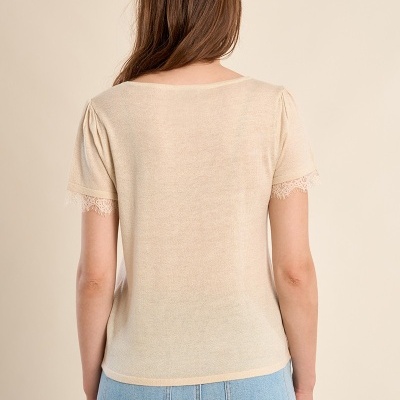 T-shirt feminina bege com renda nas mangas e calças de ganga azuis vistas de costas