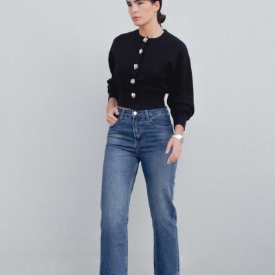 Mulher com camisola preta, jeans azul e sapatos de salto xadrez