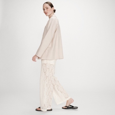 Mulher com blazer bege e calças de renda creme com sandálias pretas