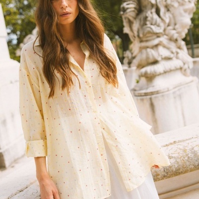 Blusa amarela clara com padrão de corações coloridos em ambiente exterior