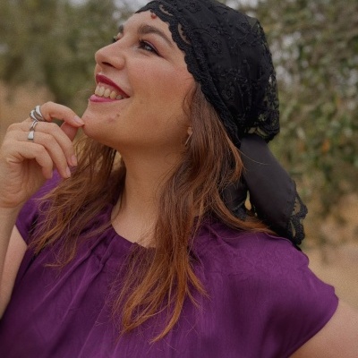 Mulher com lenço preto de renda e vestido roxo ao ar livre