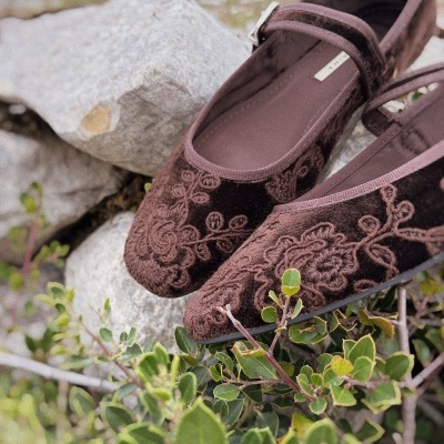 Sapatos castanhos Mary Jane com bordados florais sobre pedras e folhagem.