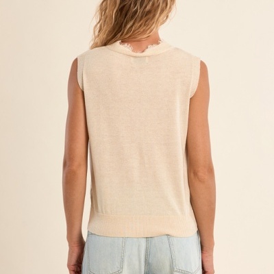 Colete de malha creme e calças de ganga azul claro vistas de costas