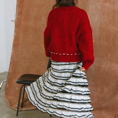 Casaco vermelho de malha grossa com saia branca com riscas pretas